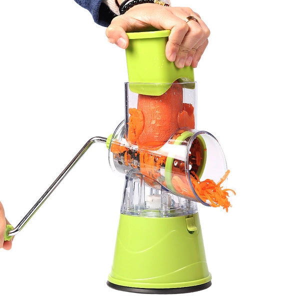Green manual drum grater with clear drum; hand pushing vegetables into the hopper