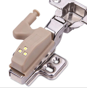 Beige LED light hinge module with three small indicator LEDs and metal mounting bracket